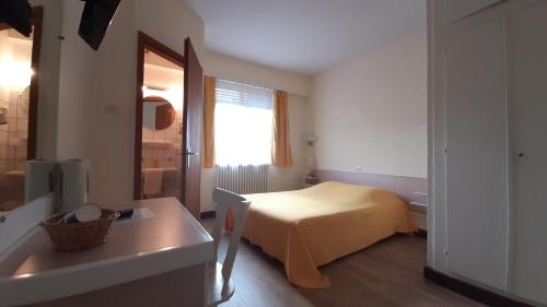 a bedroom with a bed and a table and a window at Hôtel Restaurant Aux Deux Roses in Neuf-Brisach