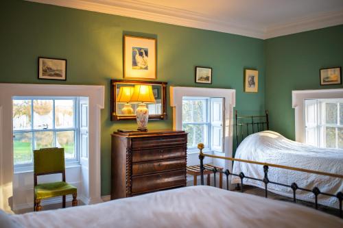 a bedroom with green walls and a bed and a dresser at Roundwood House in Mountrath