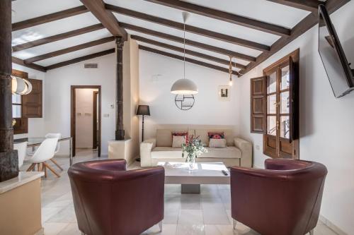 BnS Dauro Suites في غرناطة: غرفة معيشة مع أريكة وطاولة وكراسي