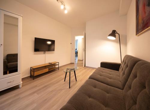 een woonkamer met een bank en een flatscreen-tv bij Gemütliches Apartment direkt am Hafen von Dortmund in Dortmund