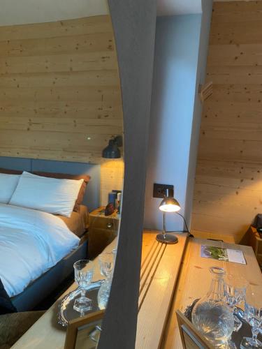 a bedroom with a bed and a table with glasses on it at B&B CAMPITELLO 13 di Caterina Costan in San Nicolò di Comelico