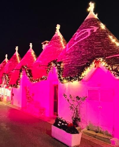 a house covered in pink lights at night at Trulli Moon in Alberobello