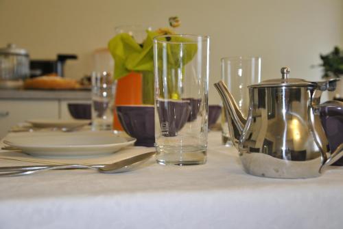 una mesa con vasos y platos y un hervidor de agua. en B&B Francesca, en Verona