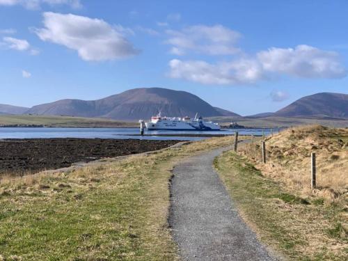 a boat docked on the water with mountains in the background at Orkney Lux Lodges - Hoy Lodge in Stromness