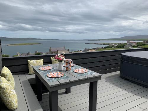 a table on a balcony with a view of the water at Orkney Lux Lodges - Hoy Lodge in Stromness