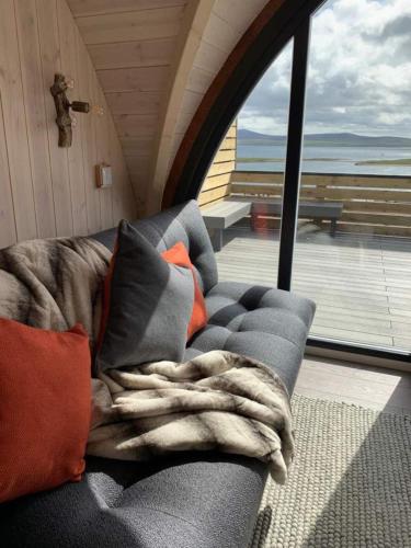 a couch with pillows and a blanket on a porch at Orkney Lux Lodges - Hoy Lodge in Stromness