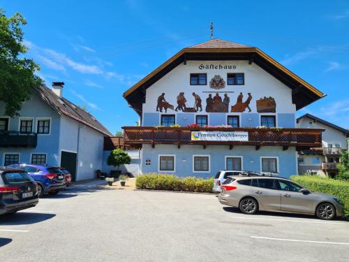 um prédio com carros estacionados em um estacionamento em Pension Göschlberger em Mondsee