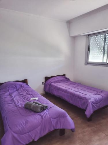 two beds in a room with purple blankets at Duplex 571 in Chascomús