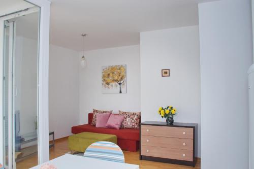 a living room with a red couch and a dresser at SunShine in Novalja