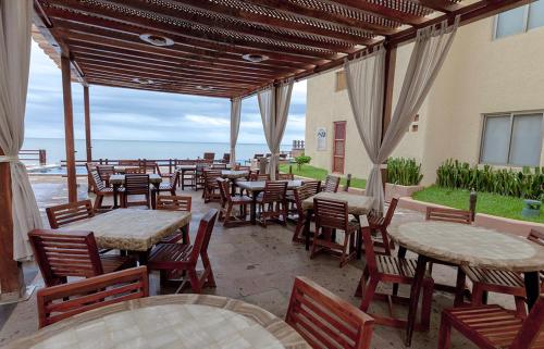 a patio with tables and chairs and the ocean at Zafiro Beach Boutique Resort in Mazatlán