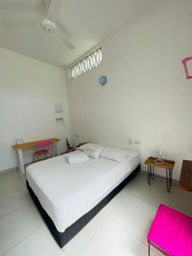 a white bedroom with a bed and two pink chairs at Casa Celeste Honda in Honda