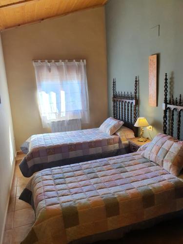 a bedroom with two beds and a window at HOTEL MASIA EL MOLINETE in Mora de Rubielos