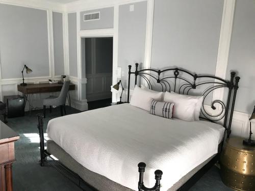 a bedroom with a bed with white pillows and a desk at River Street Inn in Savannah