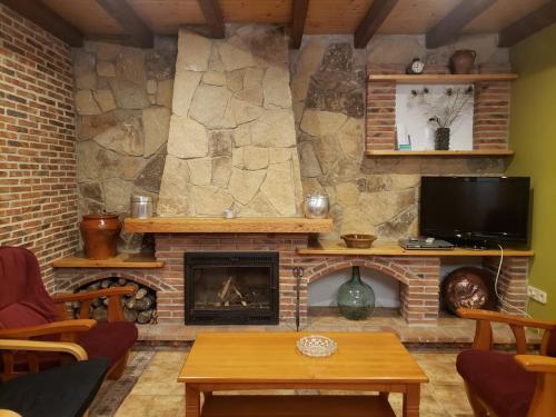 sala de estar con chimenea y TV en Los Guijos en Hoyos del Espino