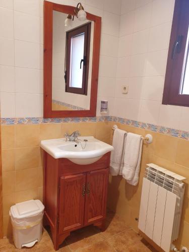 a bathroom with a sink and a mirror and a toilet at Los Guijos in Hoyos del Espino