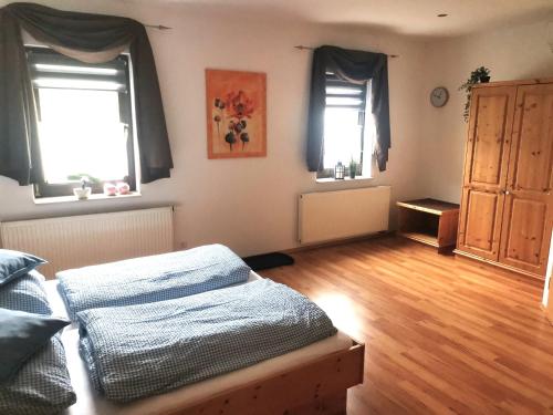 a bedroom with a bed and two windows and a wooden floor at Fraenkischer Hof in Zeitlofs