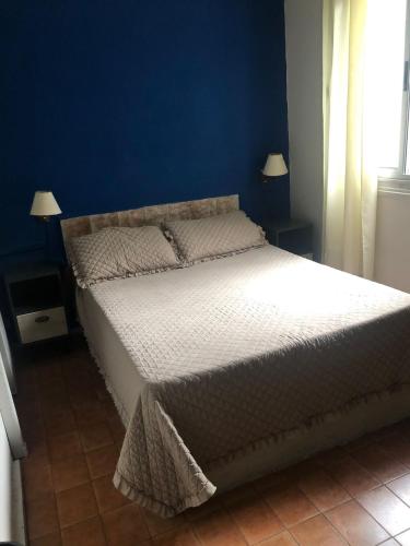 a bedroom with a large bed with a blue wall at HOTEL COMERCIO PLAYA in Montevideo
