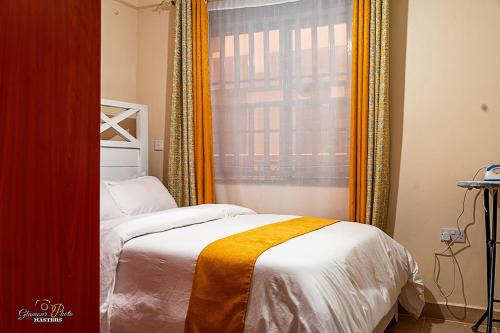 a bedroom with a bed and a window with an orange curtain at STYLISH 1BR APARTMENT IN KISUMU: FAST WI-FI, NETFLIX, SECURE PARKING in Kisumu