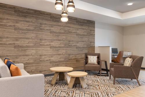 a waiting room with chairs and tables and a stone wall at Candlewood Suites - Lexington - Medical District by IHG in Lexington