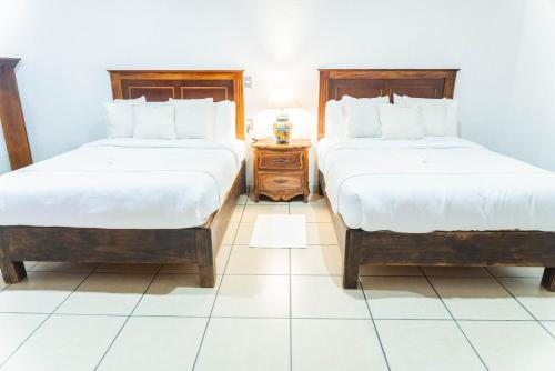 a bedroom with two beds and a table with a lamp at Casa Graciela Hotel Pátzcuaro in Pátzcuaro