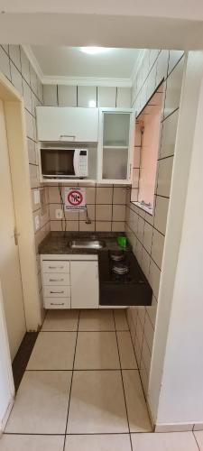a small kitchen with a sink and a microwave at diRoma Fiori - Apartamentos JN in Caldas Novas