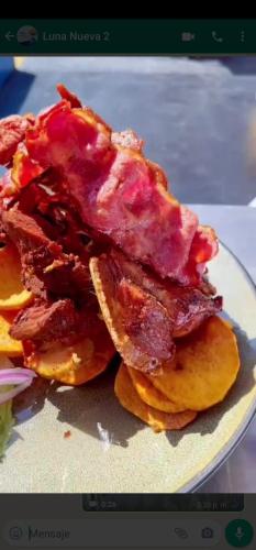 a plate of food with bacon on top of pancakes at Hotel Luna Nueva in Colán