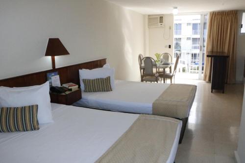 a hotel room with a large bed and a table at Alba Suites Acapulco in Acapulco