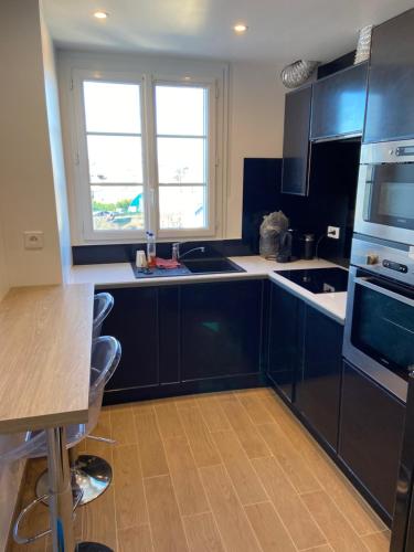 - une cuisine avec des placards noirs et un évier dans l'établissement Au bonheur des Damiettes, à Montluçon