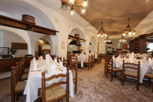 a dining room with white tables and chairs and chandeliers at Olympic Turismo Antico Borgo Hotel in Spiazzo