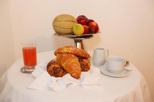 une table avec un plateau de pain et de fruits et une boisson dans l'établissement Olympic Turismo Antico Borgo Hotel, à Spiazzo