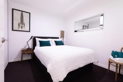 ein weißes Schlafzimmer mit einem Bett und einem Spiegel in der Unterkunft Experience Port Melbourne in Melbourne
