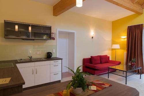 a kitchen and a living room with a red chair at Hotel Garni Pölzl in Deutschlandsberg