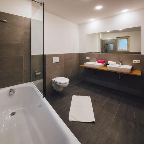 a bathroom with two sinks and a tub and a toilet at Apart Simala in Serfaus