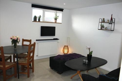 a living room with two tables and a television at Lothani Luxury Inn in Aalborg