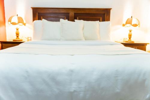 a large bed with white sheets and pillows at Casa Graciela Hotel Pátzcuaro in Pátzcuaro