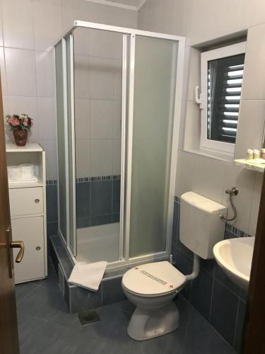 a bathroom with a shower and a toilet and a sink at Apartmani California in Podgora
