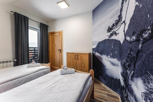 a room with two beds and a painting on the wall at Apartament Między Górami in Kacwin