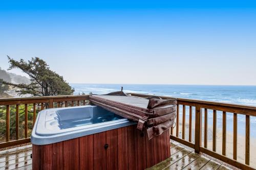 a hot tub sitting on a deck with the ocean at Blue Sea Oceanfront Cottage in Oceanside