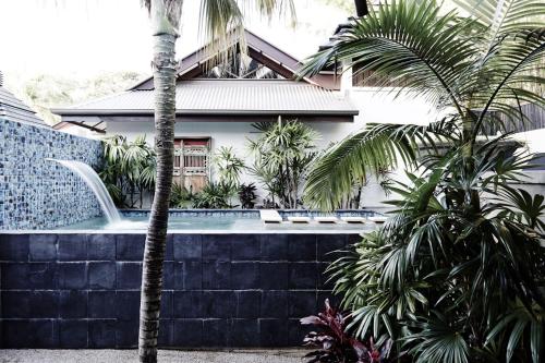 a house with a swimming pool and palm trees at The Villas of Byron in Byron Bay