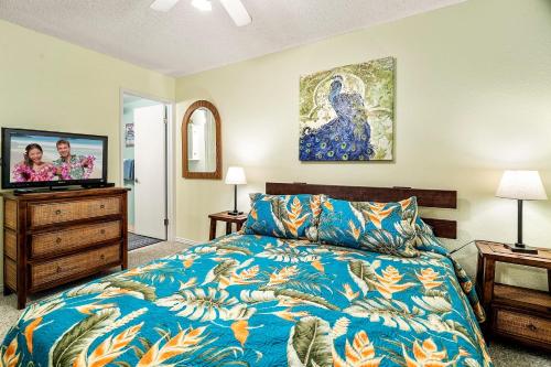 a bedroom with a bed and a flat screen tv at Sea Village #3-203 in Kailua-Kona