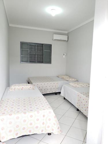 a room with three beds and a window at Pousada São Francisco in Cuiabá