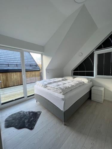 a white bedroom with a bed and large windows at Hytte på sørlandet in Kristiansand