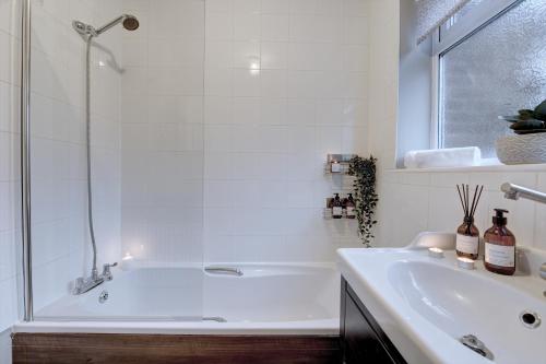 a white bathroom with a tub and a sink at Kist Accommodates - Stylish Headingley Apartment - Parking - 500 mps WIFI in Meanwood