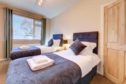 two beds in a room with a window at Kist Accommodates - Stylish Headingley Apartment - Parking - 500 mps WIFI in Meanwood