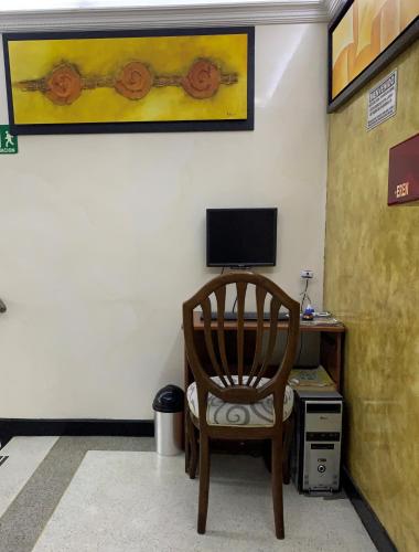 a chair sitting in front of a desk with a computer at Hotel Lourdes la 62 in Bogotá