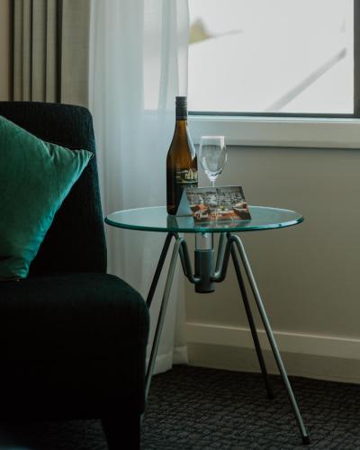 a glass table with a bottle and a wine glass at Quest Napier Serviced Apartments in Napier