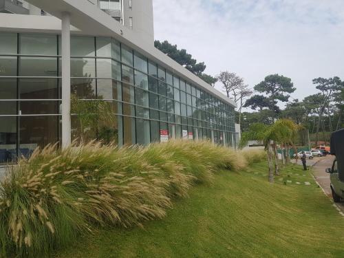 a tall glass building with grass in front of it at Ocean Drive Country - Punta del Este in Punta del Este