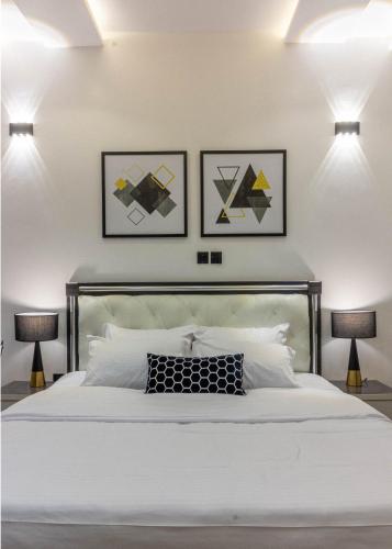 a bedroom with a white bed with three pictures on the wall at Oslo Apartment in Abuja