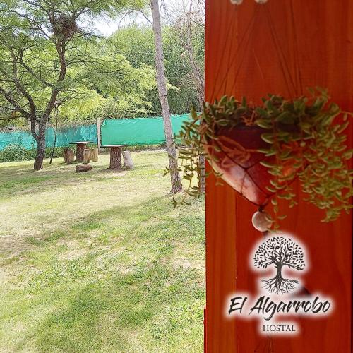 a sign with a tree on it next to a field at Hostal El Algarrobo in Casa Grande