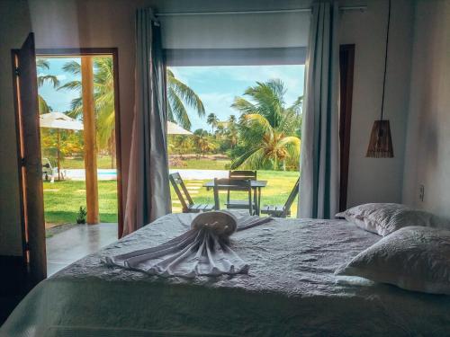 a bedroom with a bed with a view of a yard at Chalés Ed Moitas in Praia de Moitas